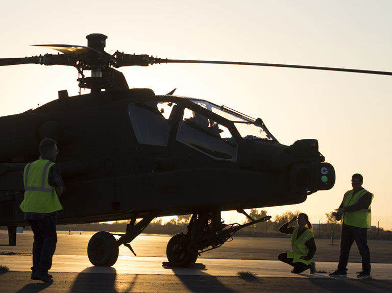 AH-64 Apache with technitians working in front and on the side of the helicopter