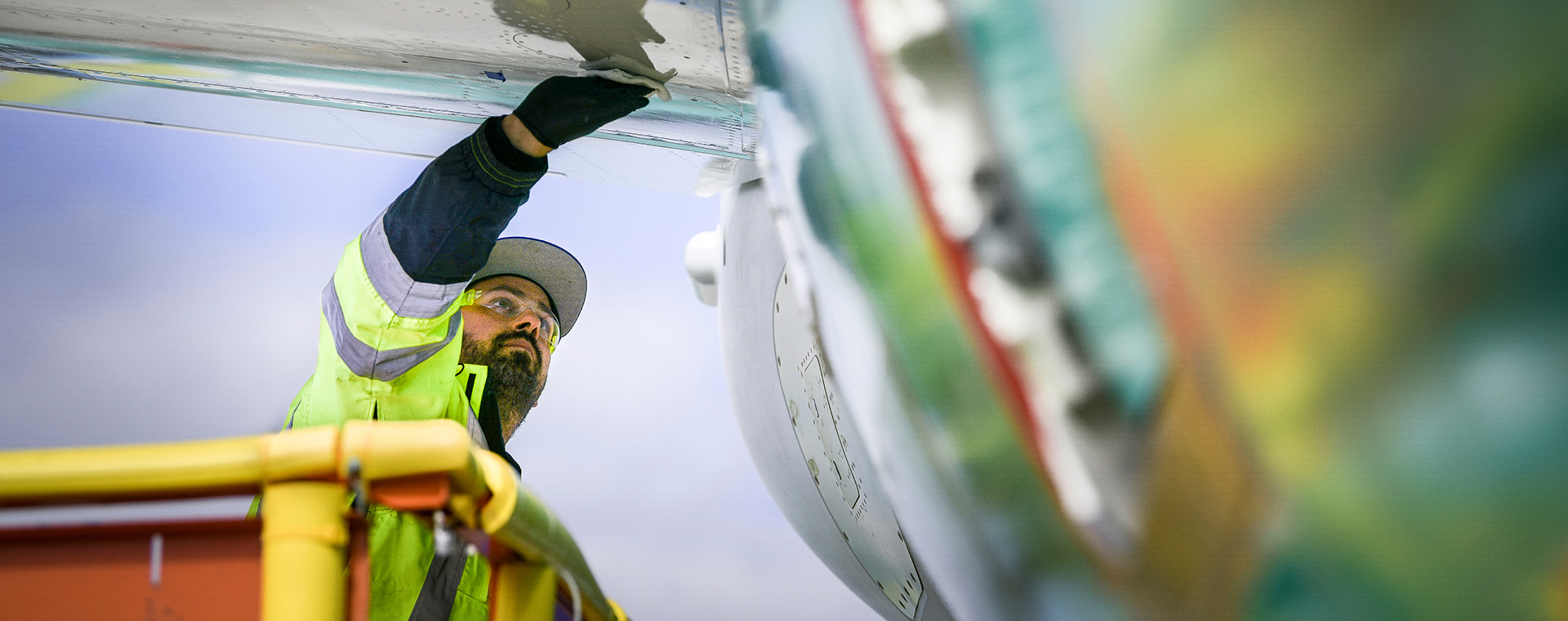 Worker in bucket lift wiping down plane exterior.