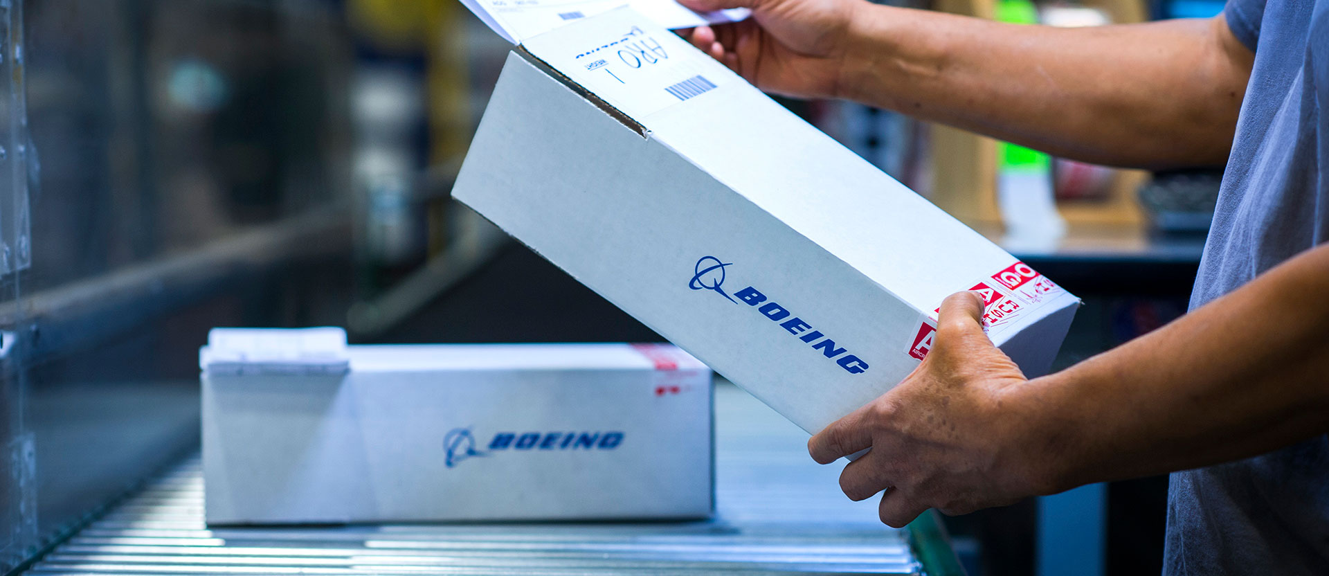 Employee handling a box of parts on a conveyer belt