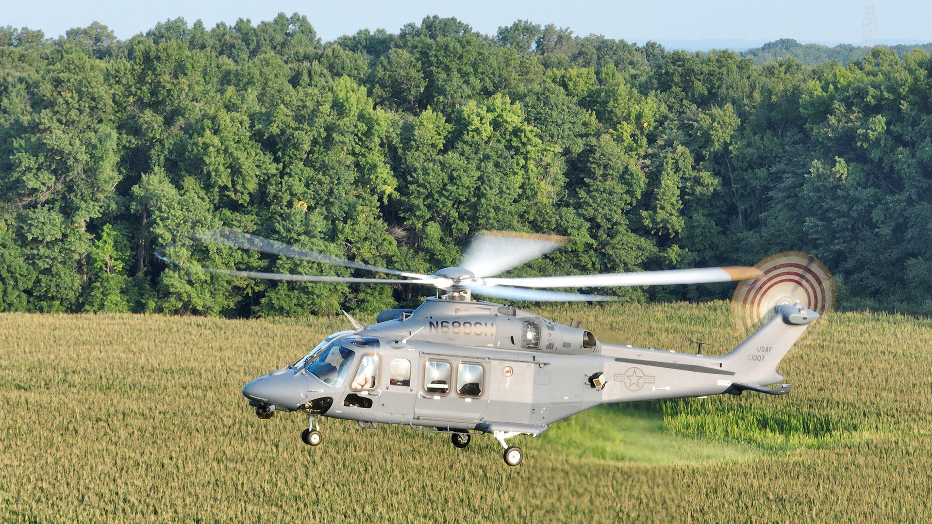 An MH-139A Grey Wolf flies over fields.