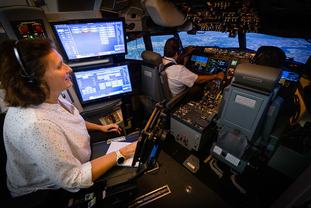 A flight simulator cockpit with an instructor, pilot and a co-pilot in flight
