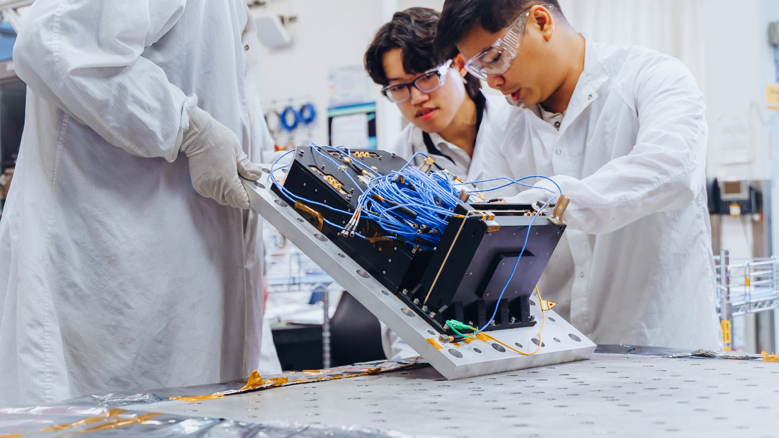 Boeing team members inspect the Q4S flight payload during testing designed to verify the hardware can withstand launch and on-orbit conditions ahead of its planned 2027 mission.