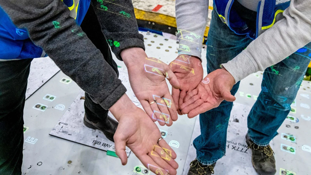 Boeing employees hold their hands out to show the light-projected instructions